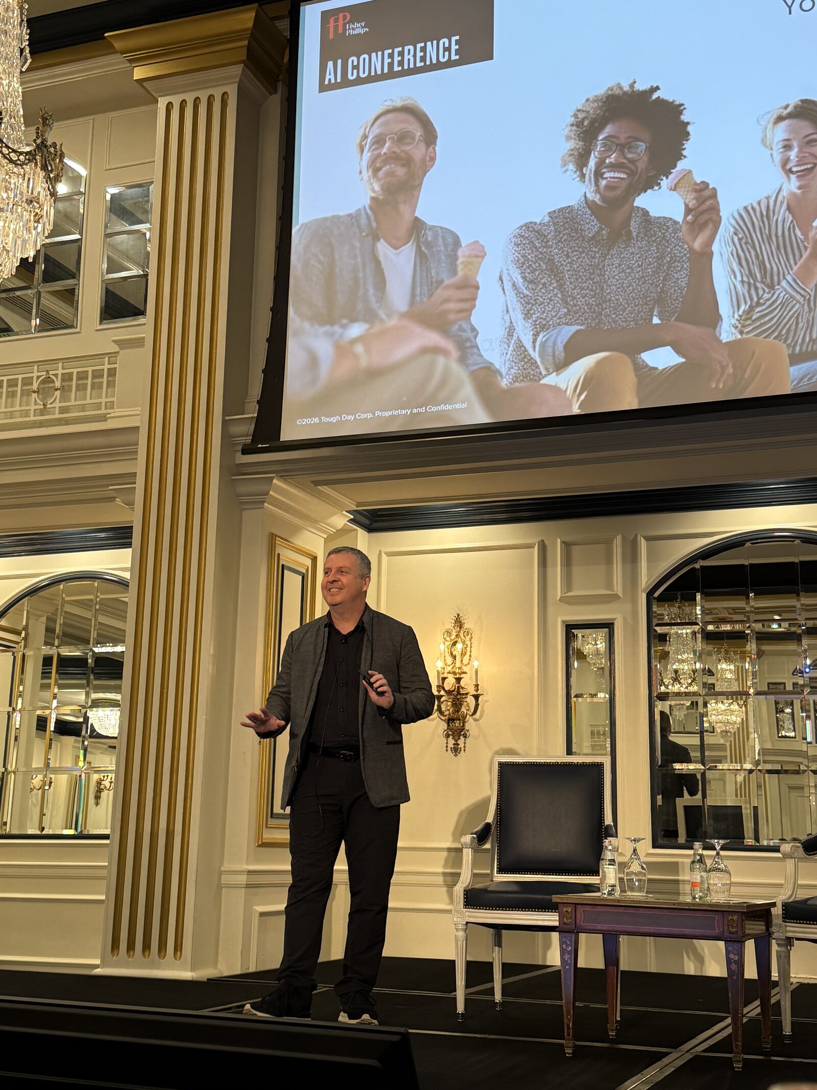 Alberto on stage at the Fisher Phillips AI Conference, presenting a Tough Day slide in a gilded ballroom