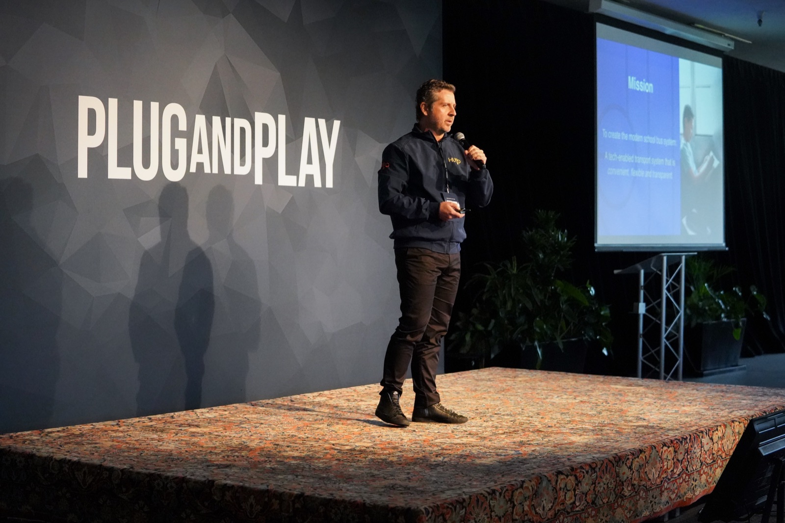 Alberto on a wide stage at Plug and Play, addressing an audience